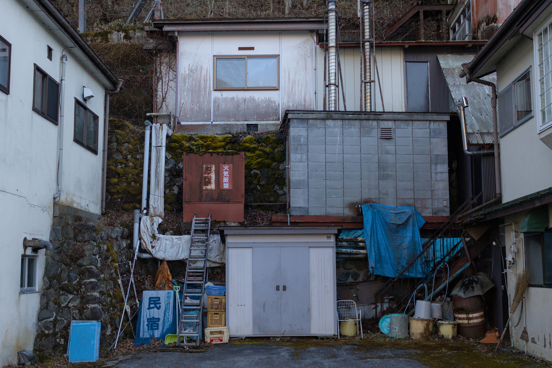 Dense and staggered layout of a few buildings and utility boxes in an alley's end.